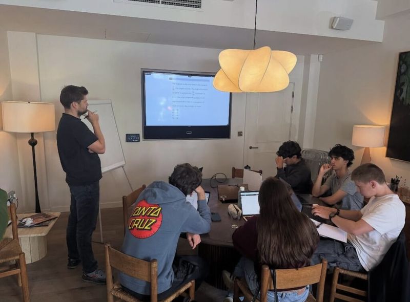 Dan Lerman teaches an SAT boot camp session in London as students work at a shared table.